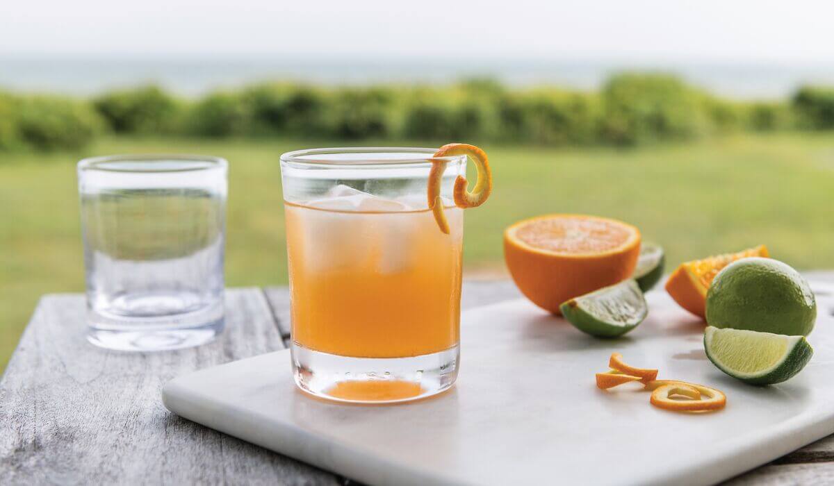 Ascutney Whiskey set against a summer gathering with oranges and limes for mixed drinks