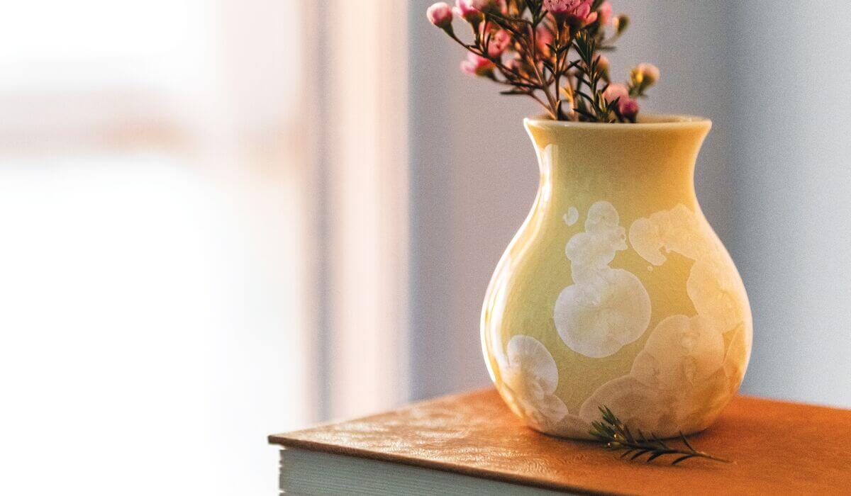 jasper yellow curio bud vase with pink flowers coming out of it